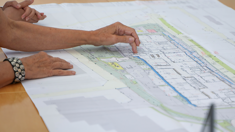 Bauplan auf dem Tisch mit Händen Bauplan auf dem Tisch mit Händen