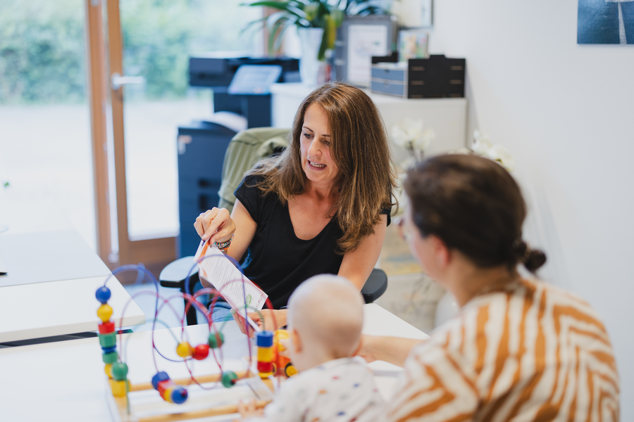 Familienberatung, eine Beraterin mit Baby und Mutter Familienberatung, eine Beraterin mit Baby und Mutter