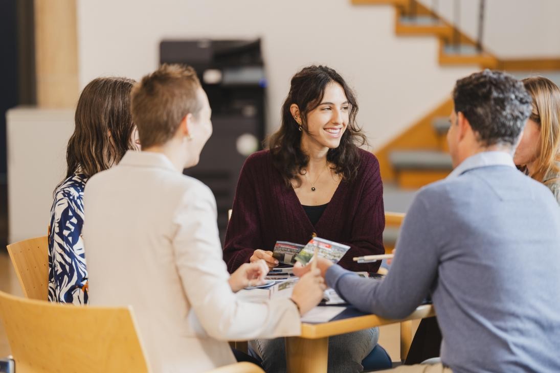 5 Personen unterhalten sich an einem Tisch.